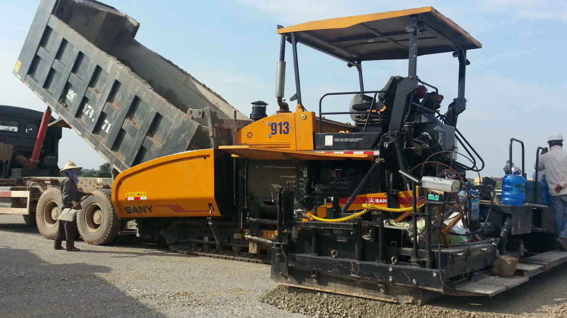 The truck is dumping materials into the SANY paver